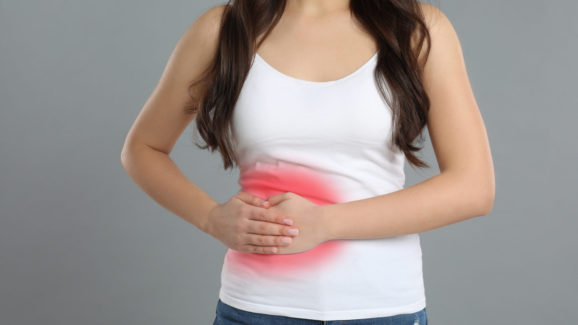 Young woman suffering from liver pain on grey background, closeu