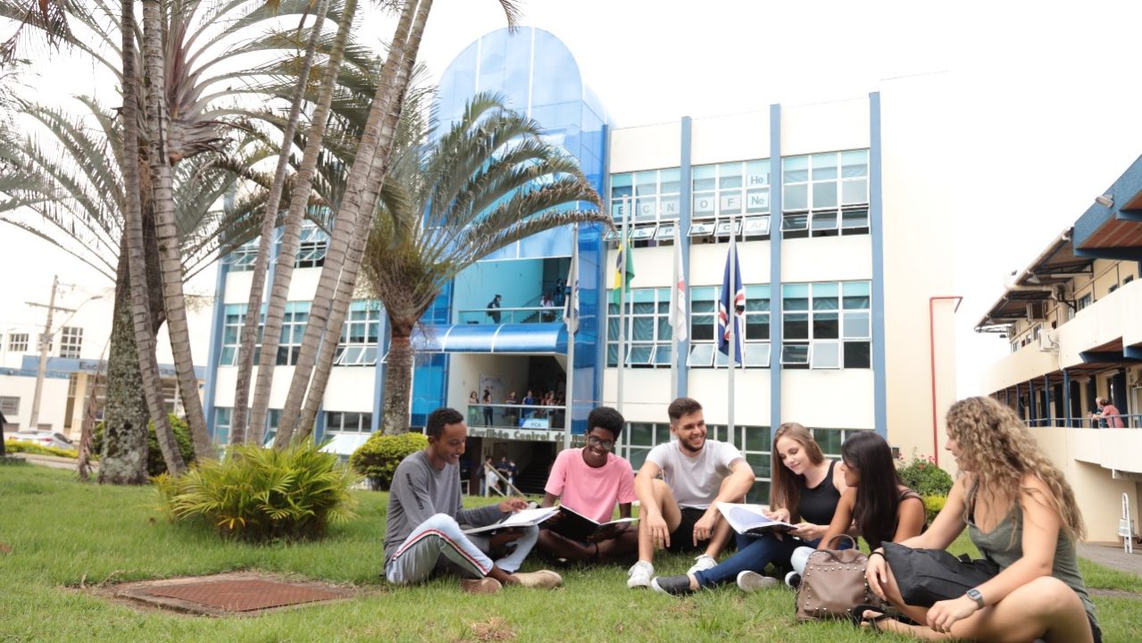 Grupo de estudantes sentados em círculo na área externa da Unifal-MG, em momento de estudo e conversa.