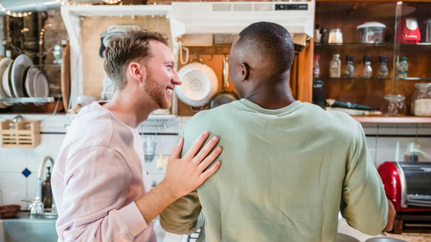 Casal de homens sorri em ambiente doméstico