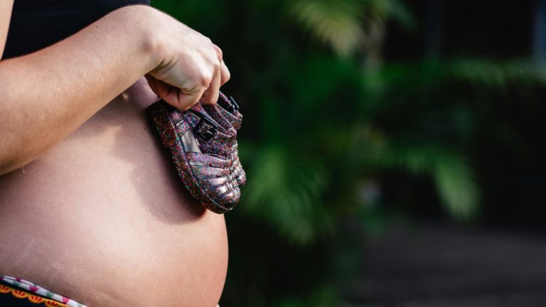 pexels-doouglasma-18978102 Adolescente grávida segura sapatinhos infantis sobre a barriga