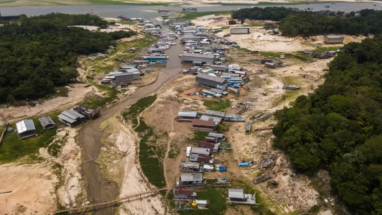 54_retro_2023_seca_no_amazonas Comunidade ribeirinha na Amazônia com barcos encalhados e rio seco durante forte estiagem, evidenciando os efeitos das mudanças climáticas.
