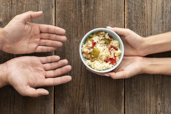 hand-giving-bowl-food-needy-person Mãos estendidas recebem um prato simples de comida, simbolizando o impacto da alta dos preços e a desigualdade no acesso à alimentação.