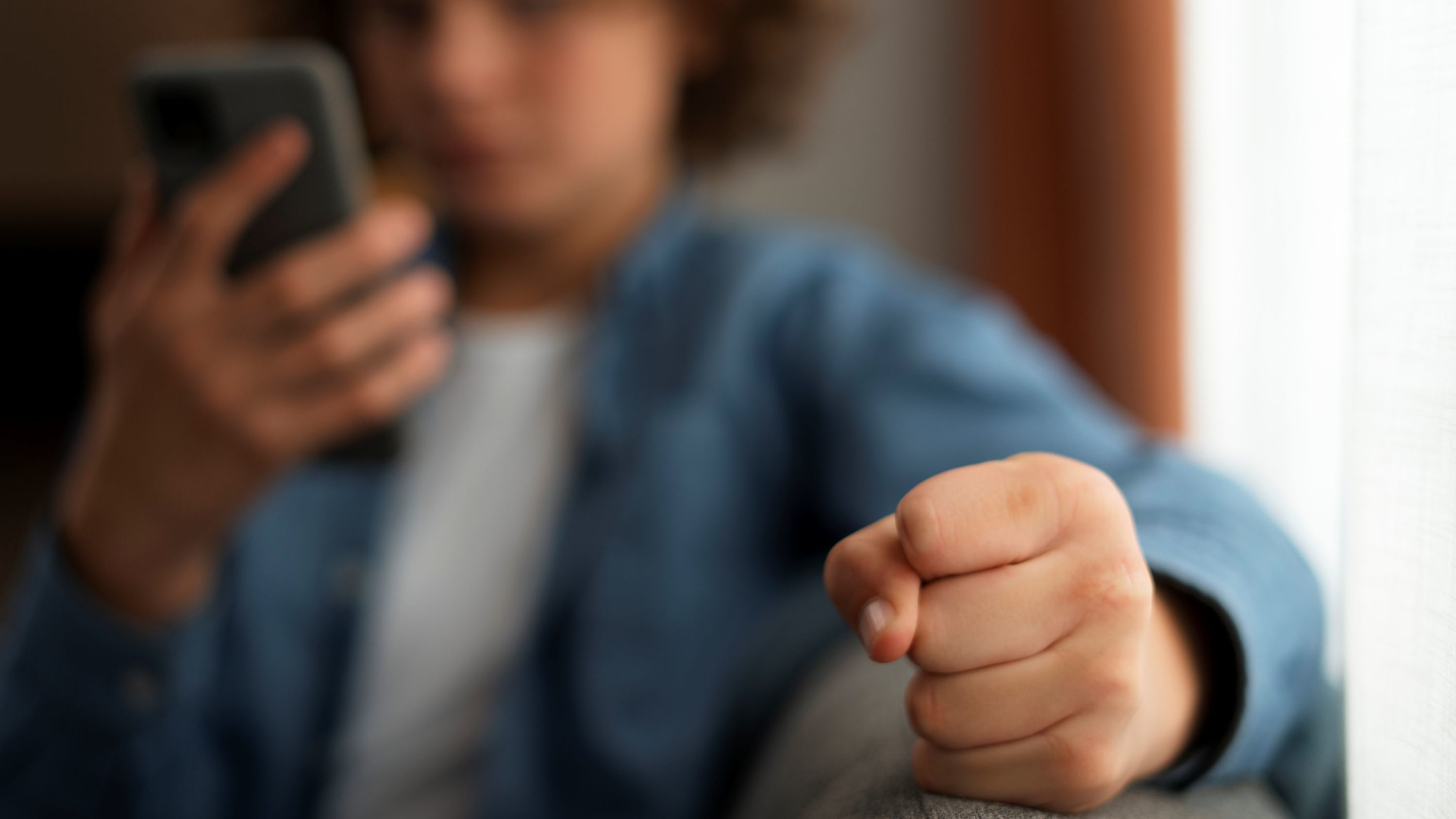 sad-teenager-being-cyberbullied-front-view Adolescente segura o celular com expressão de tensão, simbolizando o impacto emocional da violência online e do cyberbullying