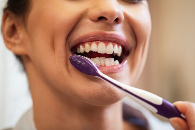 Close da boca de uma mulher escovando os dentes