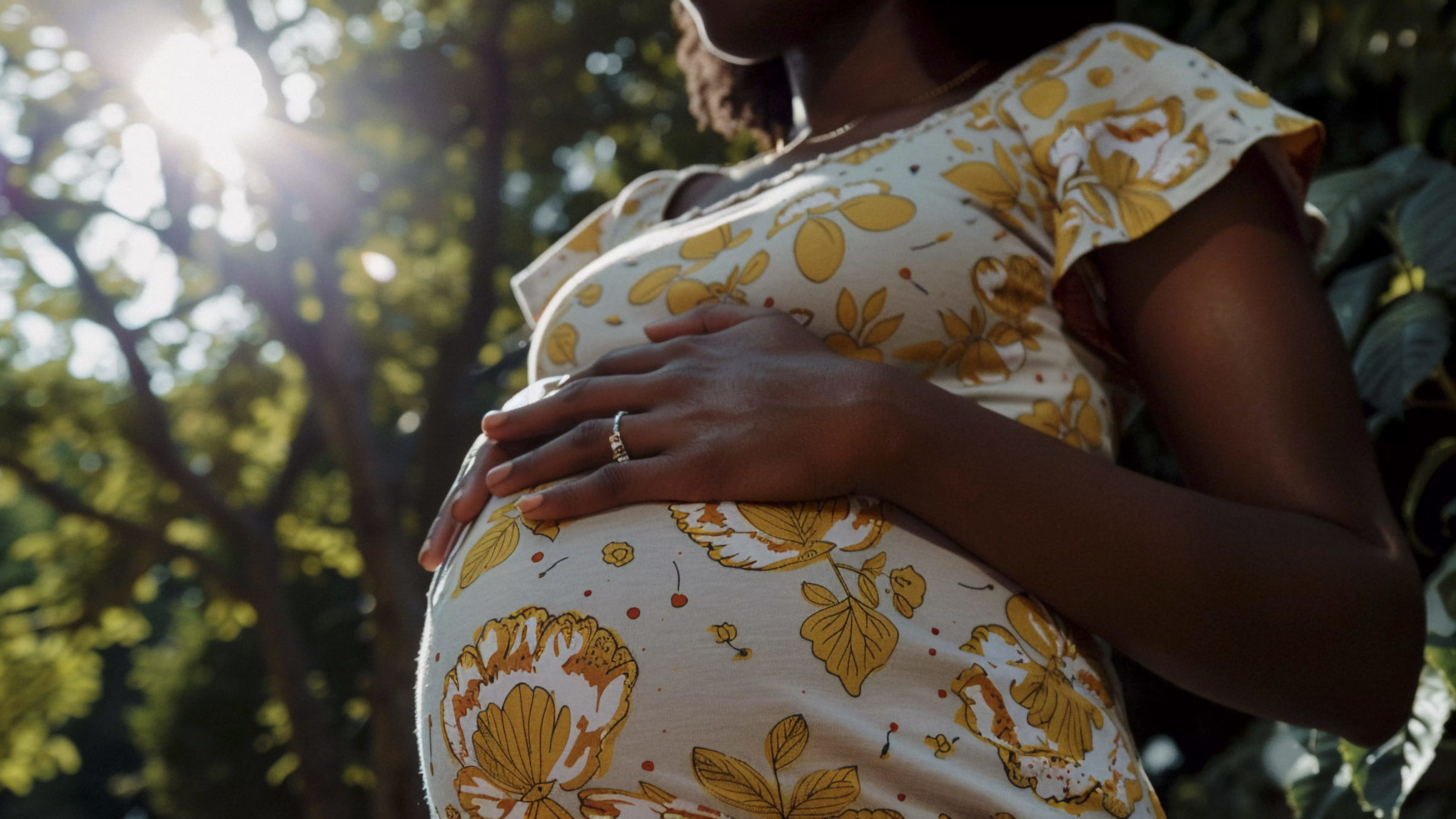 black-pregnant-women-posing Mulher grávida com as mãos apoiadas na barriga em ambiente externo, representando acompanhamento pré-natal.
