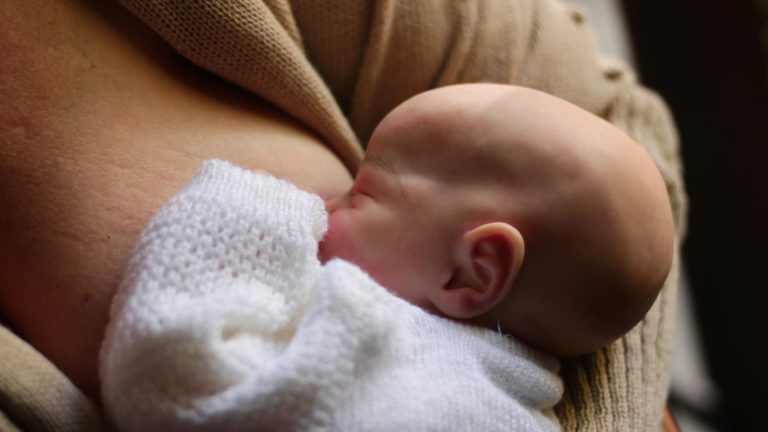 pexels-blondfox-32830536 Bebê recém-nascido amamentando no colo da mãe, visto de perfil, com foco na sucção e no contato boca-seio